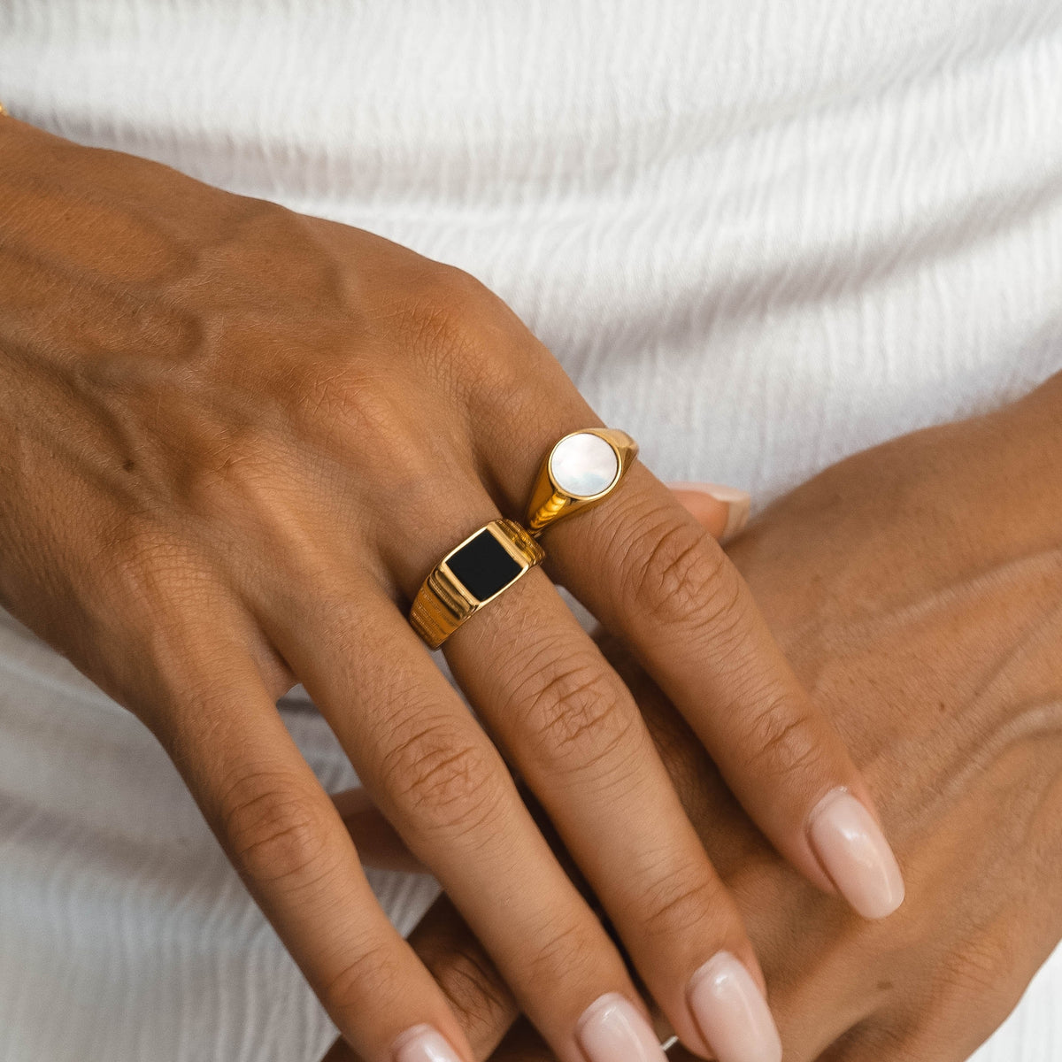 Black onyx and mother of pearl signet rings worn on the hand